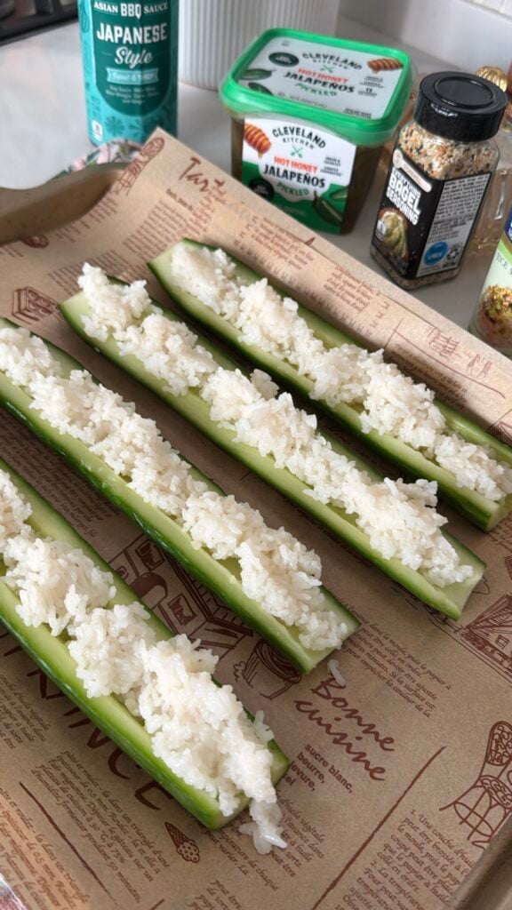 Cooked short-grain sushi rice spread in the hollowed out cucumbers
