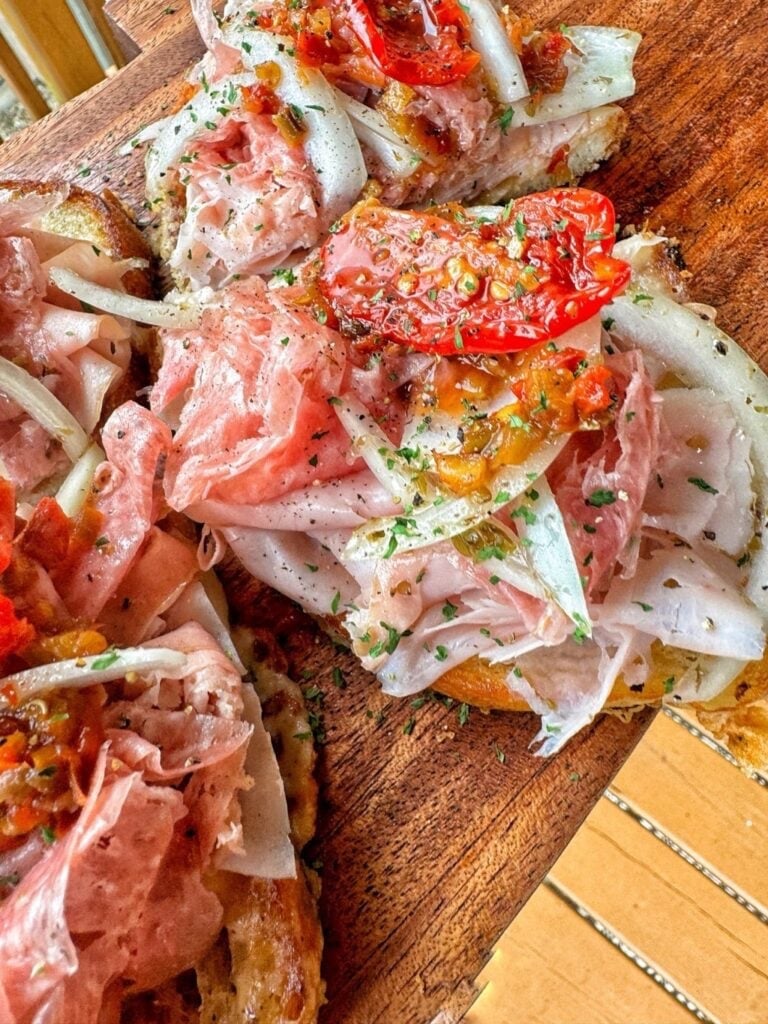 open faced Italian subs with shaved ham, onions, tomatoes and dried Italian herbs