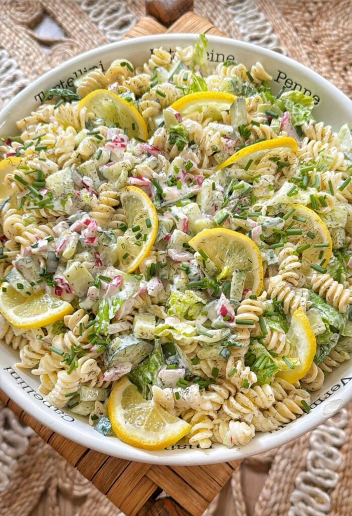A lemon pasta salad in a bowl with lemon slices and onions.