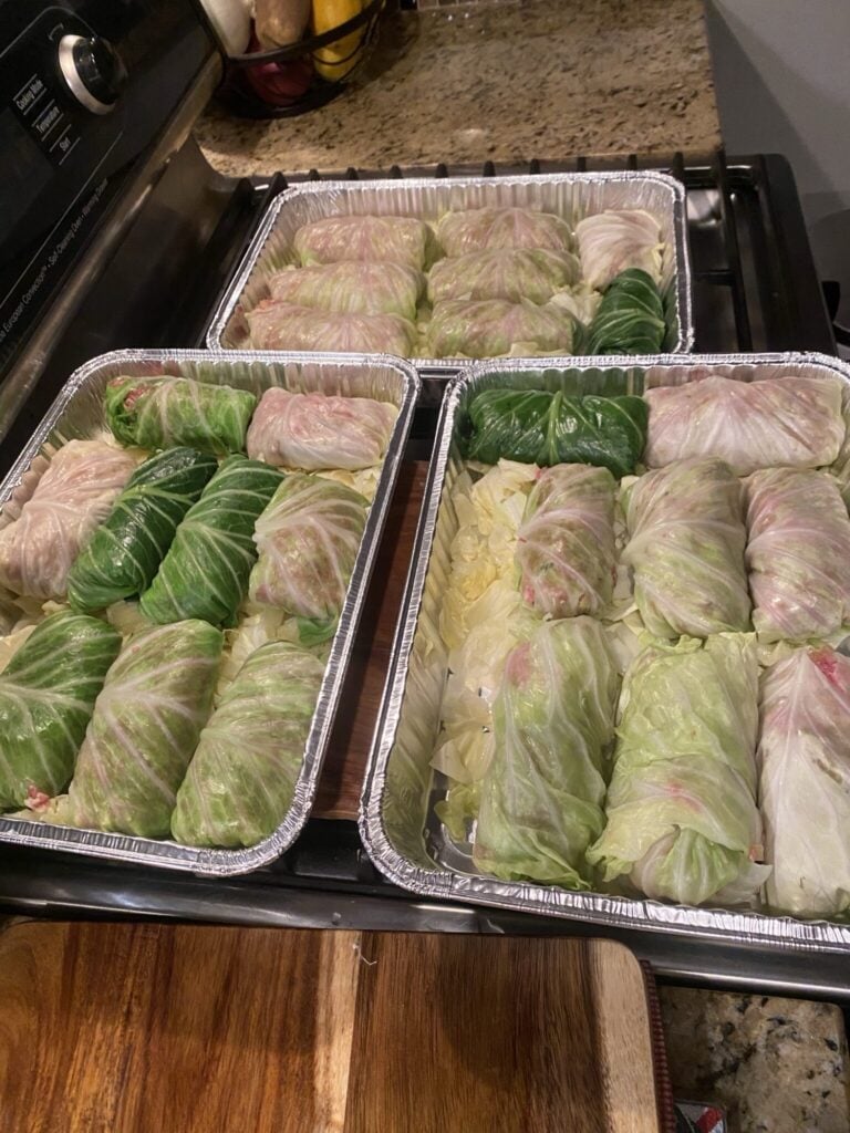 3 metal pans of stuffed and rolled cabbage leaves before baking