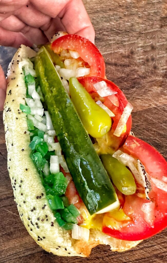 a Chicago style hot dog with relish, poppy seed bun, tomatoes pickles, onions and sport peppers