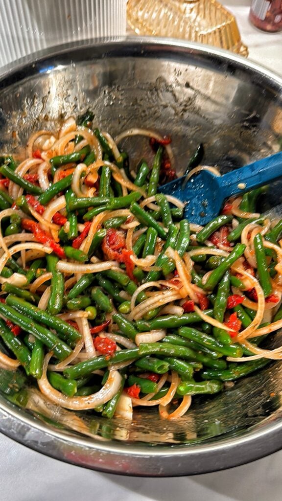 Cold green bean salad with sliced sweet onions and sun-dried tomatoes in an Italian herb dressing.