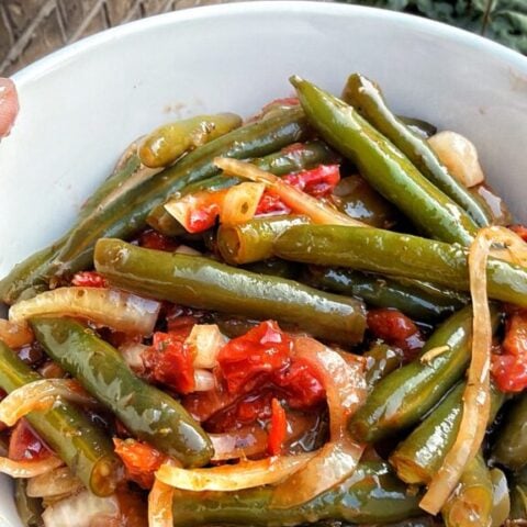 Green beans, thin slices of sweet onion, and strips of sun-dried tomato coated in dressing.