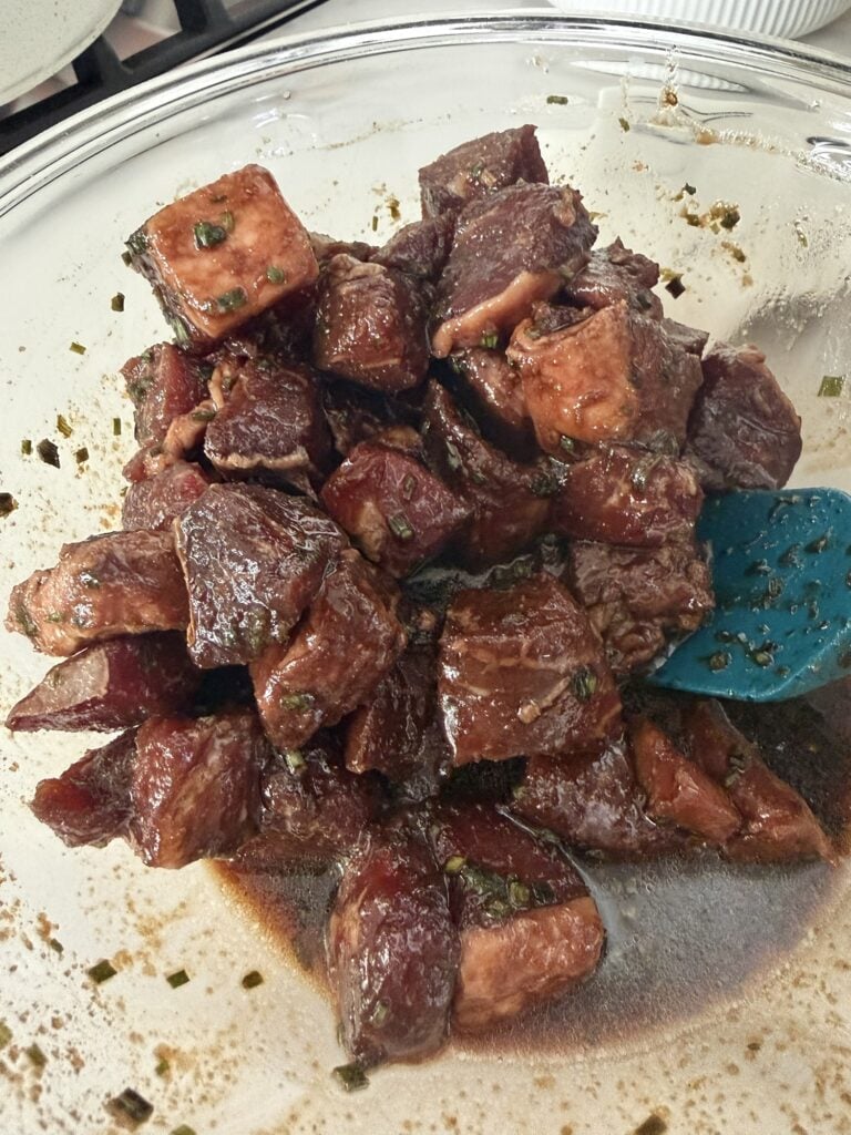 Cubes of raw sirloin steak coated in a soy sauce and chive marinade.