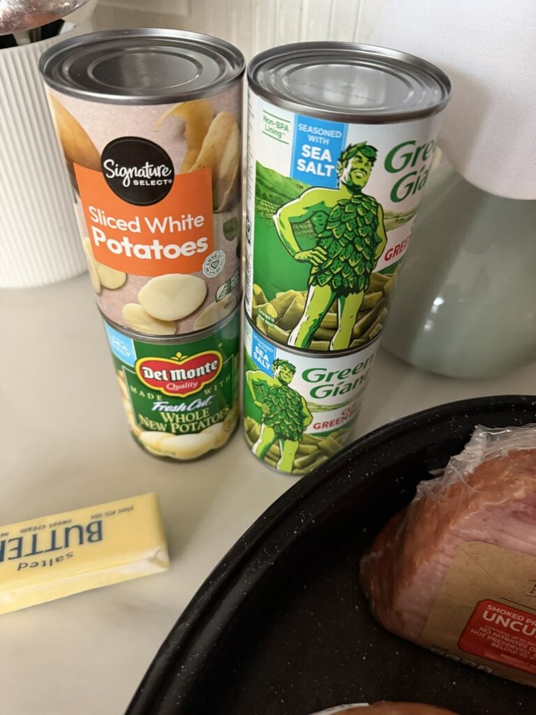 cans of sliced potatoes and green beans shown next to the roaster and a stick of butter