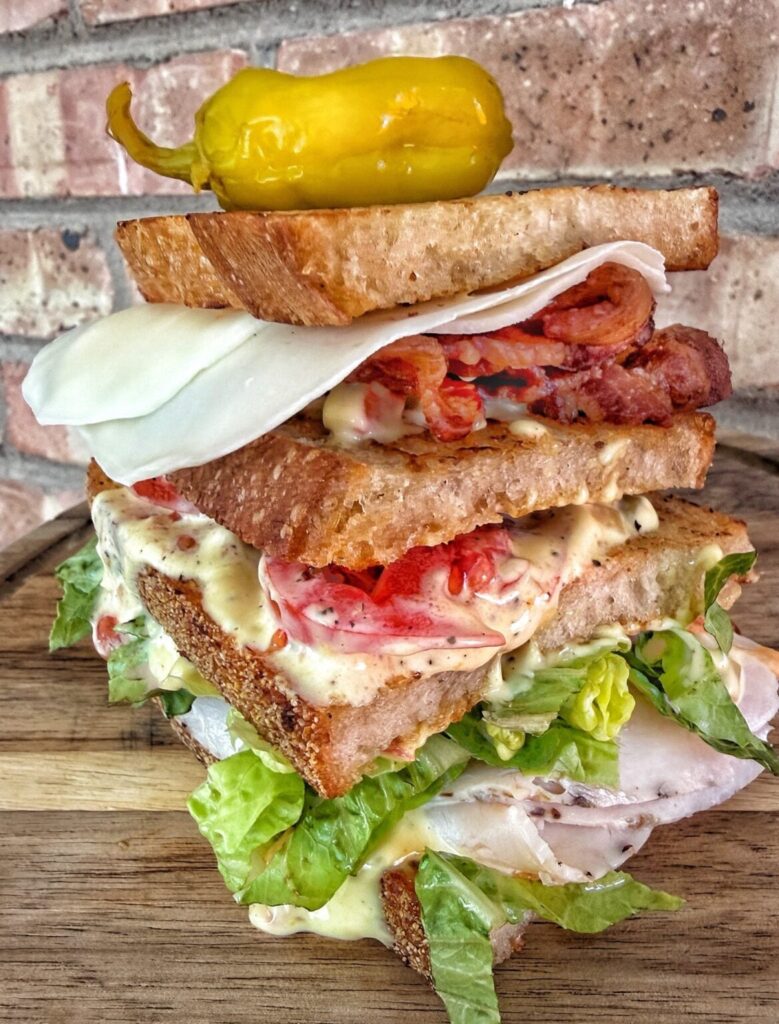 a chicago style club sandwich on toasted bread with cold cuts and cheese