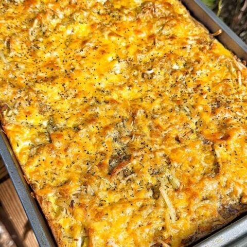 Golden cheddar cheese covering a sheet pan hash brown and egg bake.