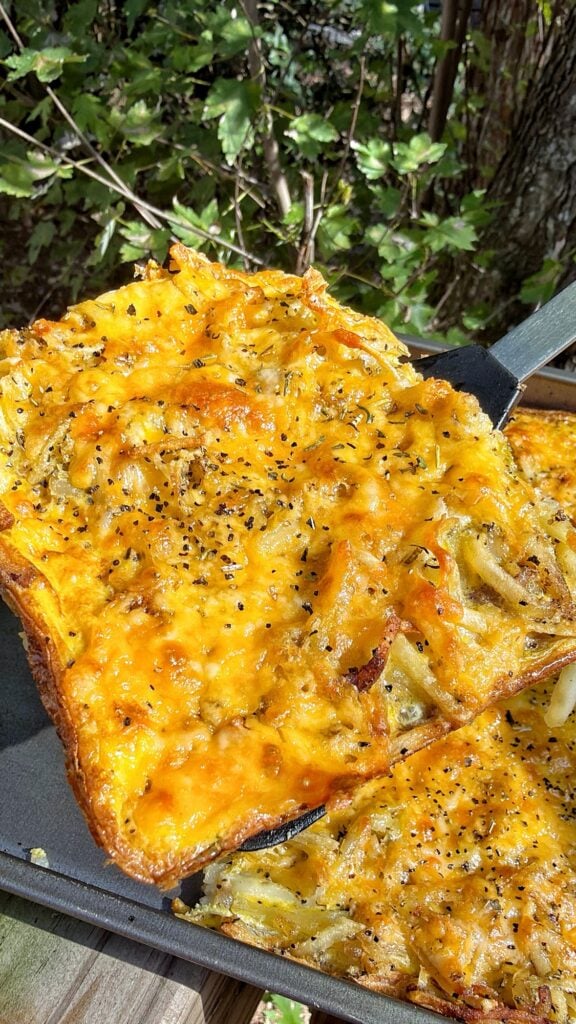 Closeup of sliced hash brown and egg bake with melted cheddar and browned edges.