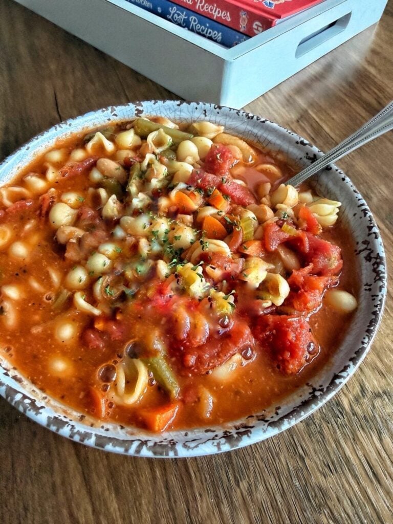 a bowl of classic minestrone soup with pasta, tomatoes and vegetables