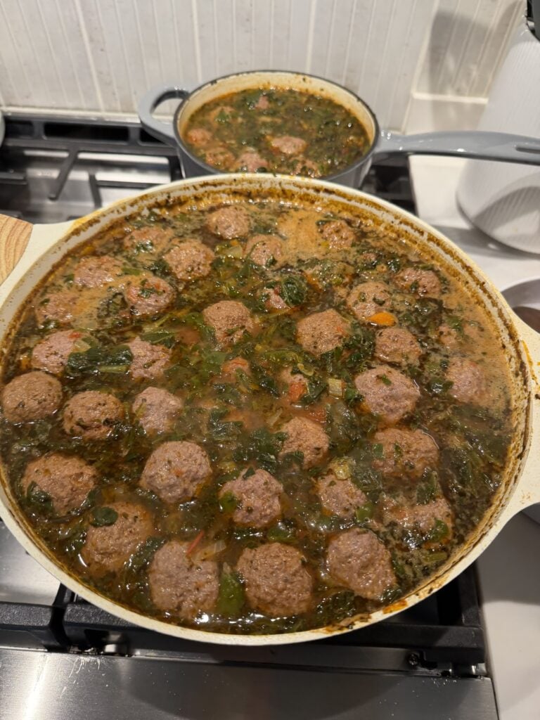 Beef broth with finely diced vegetables and dried herbs simmering in a pot.