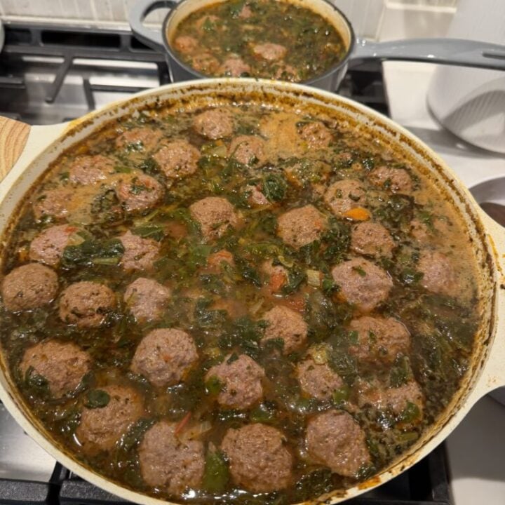 Beef broth with finely diced vegetables and dried herbs simmering in a pot.